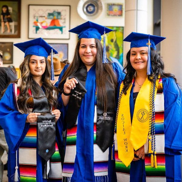 三个穿着蓝色毕业礼服和拉丁裔披肩的女人