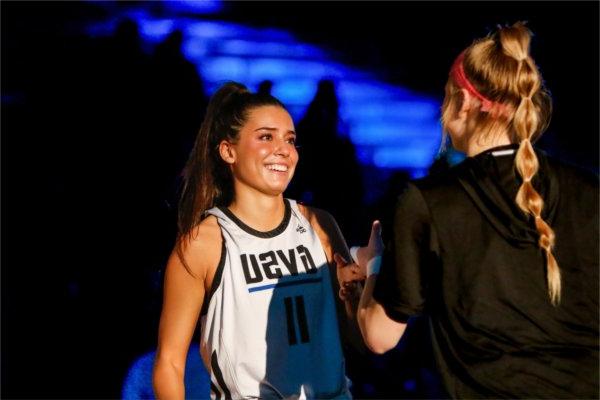  一位大学女篮球运动员在比赛开始前微笑并做了一个特殊的握手. 